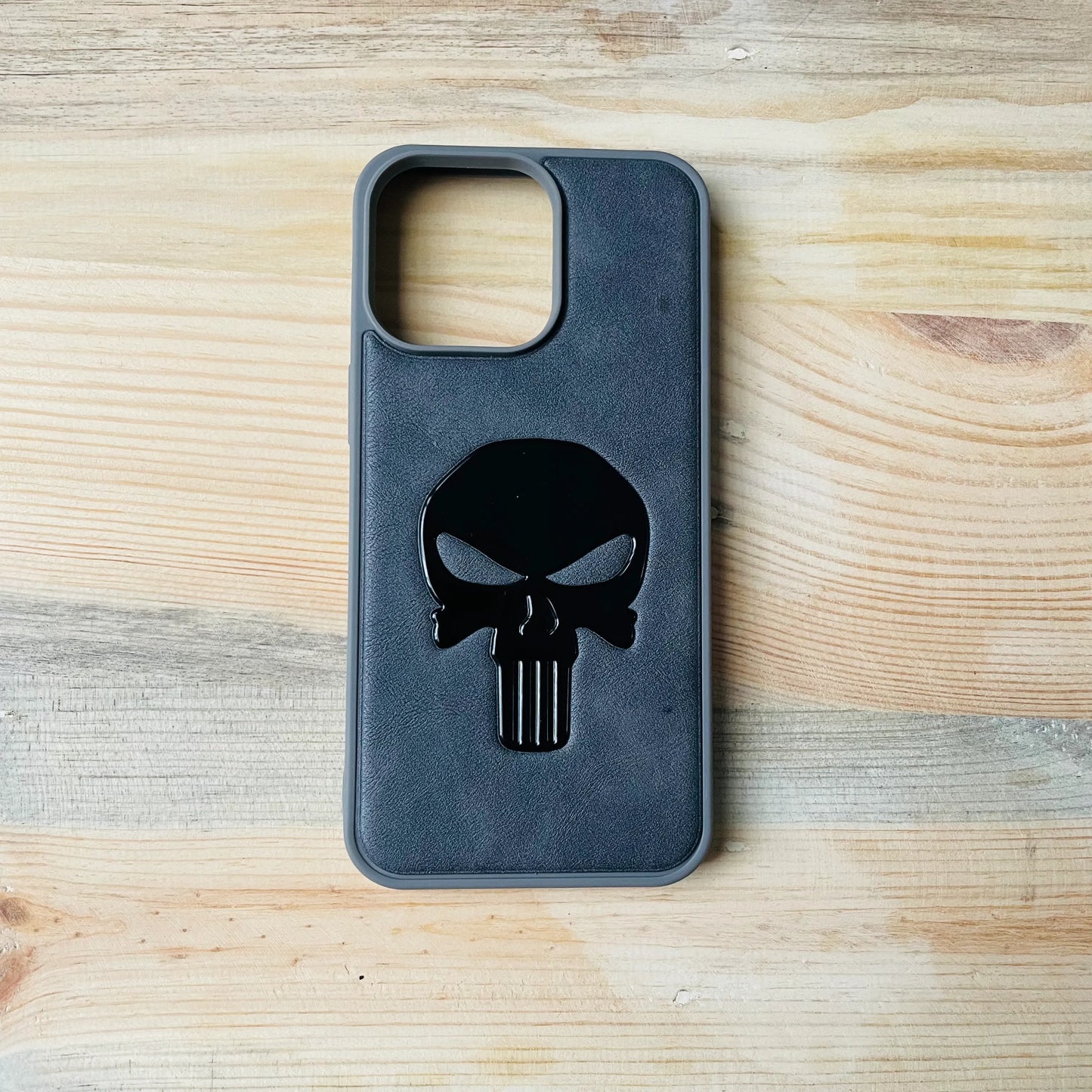 Gray Series Premium Leather 3D Embossed iPhone case with Punisher skull design on a wooden surface