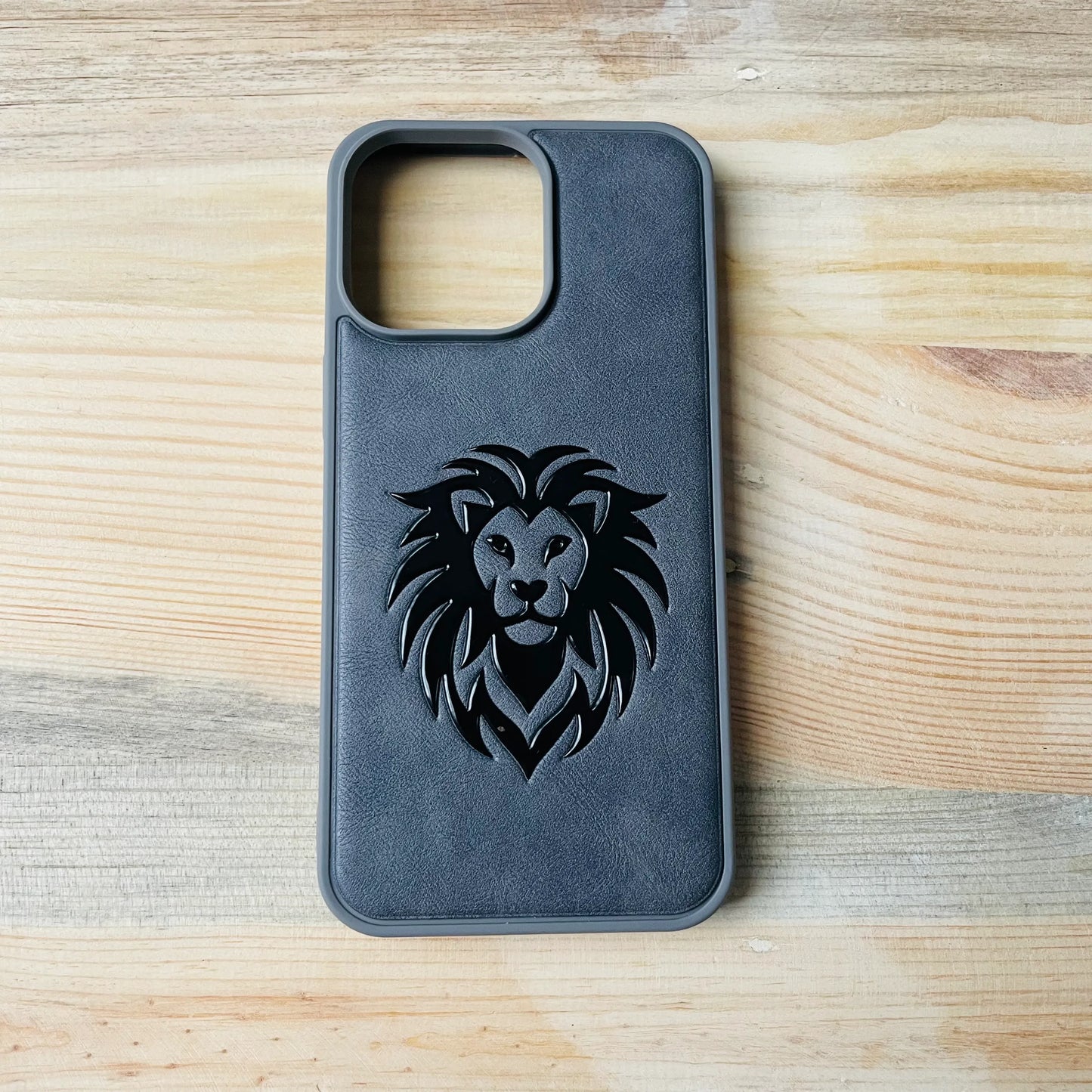 Gray Series | Premium Leather 3D Embossed iPhone  case with a lion design on a wooden surface